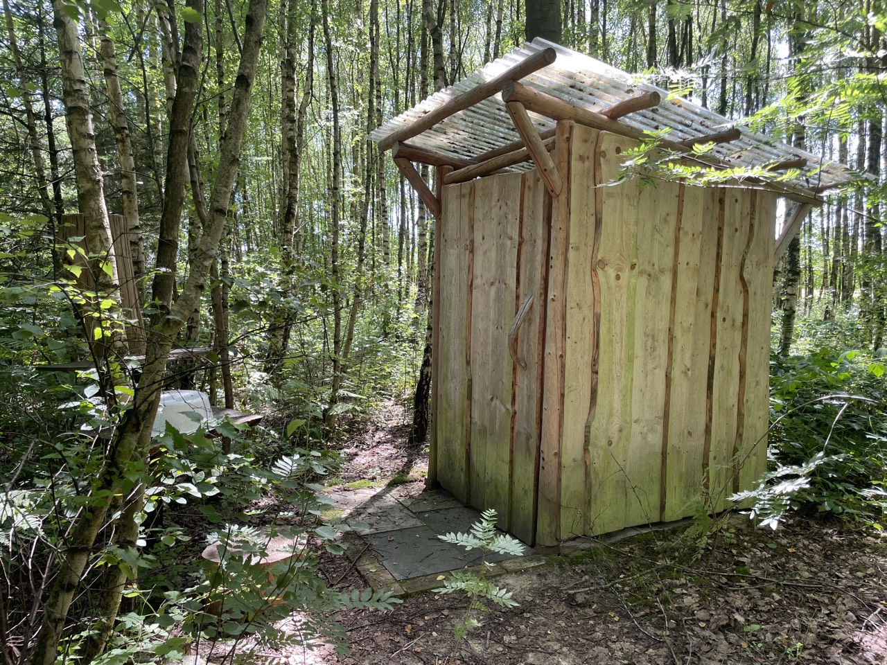Selbstgebaute Kompost-Toilette aus Holz im Wald des Kursgeländes