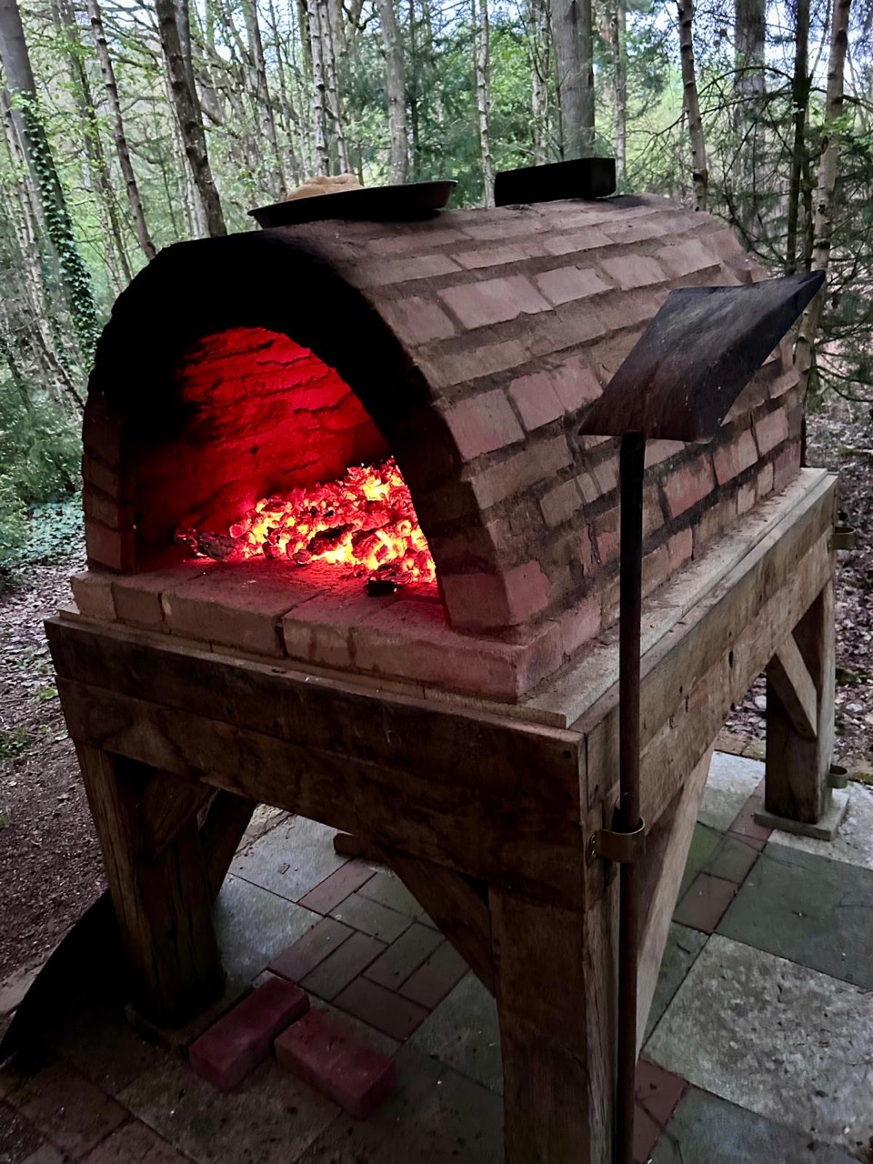 Selbstgebauter Holzbackofen mit glühender Glut im Wald des Kursgeländes