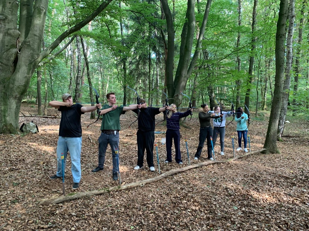 Gruppe beim Bogenschießen im Wald auf dem Kursgelände
